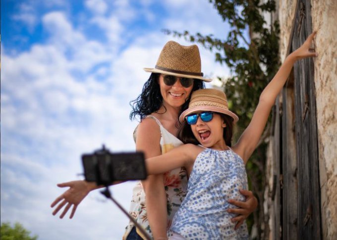 Kobieta z córką na wczasach korzysta z naturalnego światła do zrobienia selfie przy pomocy selfie sticka