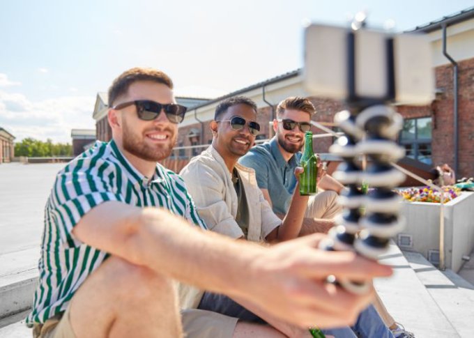 Mężczyźni przy piwie robią sobie selfie z wykorzystaniem selfie sticka ze stabilizatorem