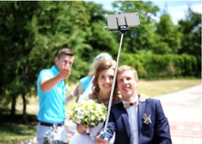 Para młoda na ślubie roi sobie selfie przy pomocy selfie sticka