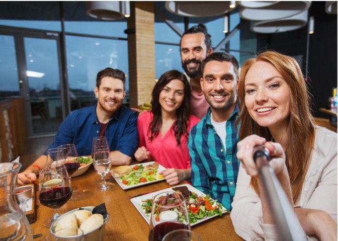 Znajomi na imprezie robią sobie zdjęcia przy pomocy selfie sticka